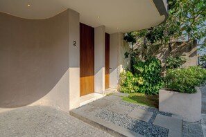 A modern building entrance with a stone pathway, a wooden door, and a number '2' on the wall. - Lumea Canggu by Pertama Stay (Canggu)
