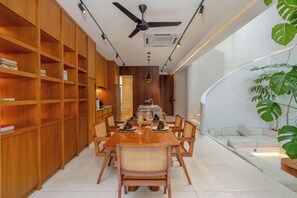 A modern dining area with a wooden table, chairs, and a ceiling fan. - Lumea Canggu by Pertama Stay (Canggu)