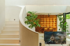 A modern interior with a curved staircase, a dining area with wooden furniture, and a large framed picture on the wall. - Lumea Canggu by Pertama Stay (Canggu)