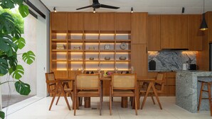 A modern kitchen with wooden cabinets, a marble island, and a dining area with wooden chairs. - Lumea Canggu by Pertama Stay (Canggu)