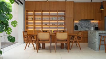 A modern kitchen with wooden cabinets, a marble island, and a dining area with wooden chairs.