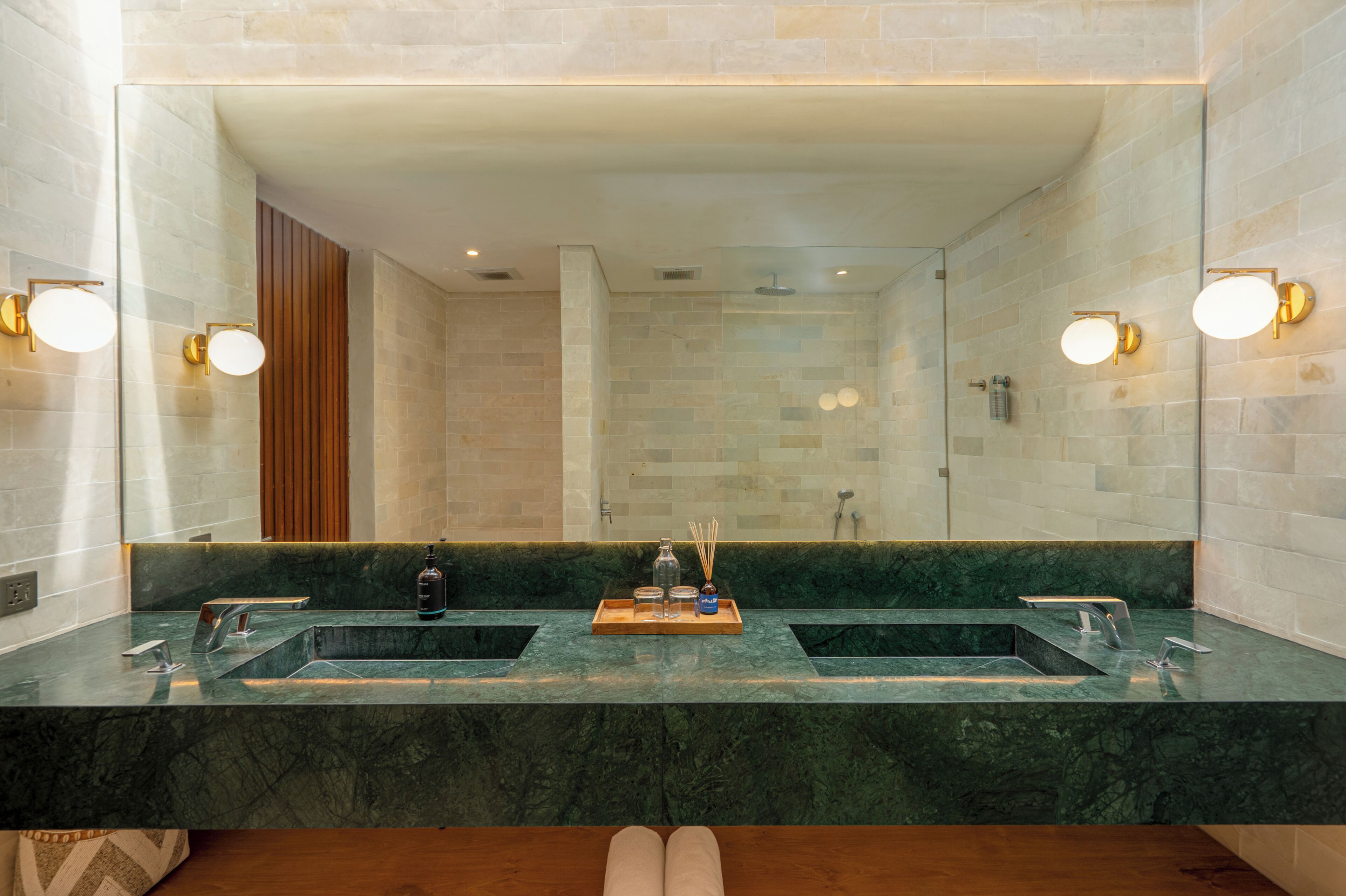 A bathroom with two sinks, a mirror, and a shower.