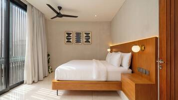 A modern bedroom with a bed, ceiling fan, wall art, bedside lamp, and a view through a large window.