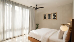 A modern bedroom with a bed, a ceiling fan, and artwork on the wall. - Lumea Canggu by Pertama Stay (Canggu)