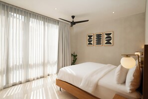 Ein modernes Schlafzimmer mit einem Bett, Deckenventilator und Kunstwerken an der Wand.