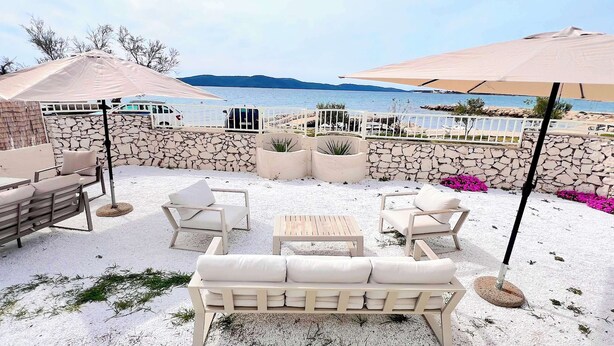 A patio with outdoor furniture, a stone wall, and a view of the sea. - Luxury Beach Villa, Sibenik, 4 Stars (Brodarica)
