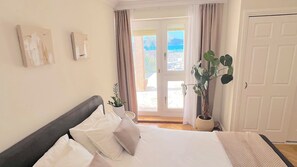 A bedroom with a bed, a potted plant, and a view through a door.