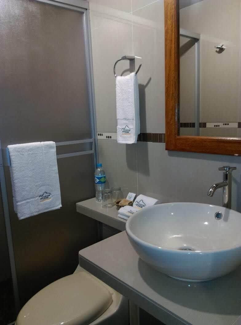 A bathroom with a toilet, a sink, a mirror, and a towel rack.