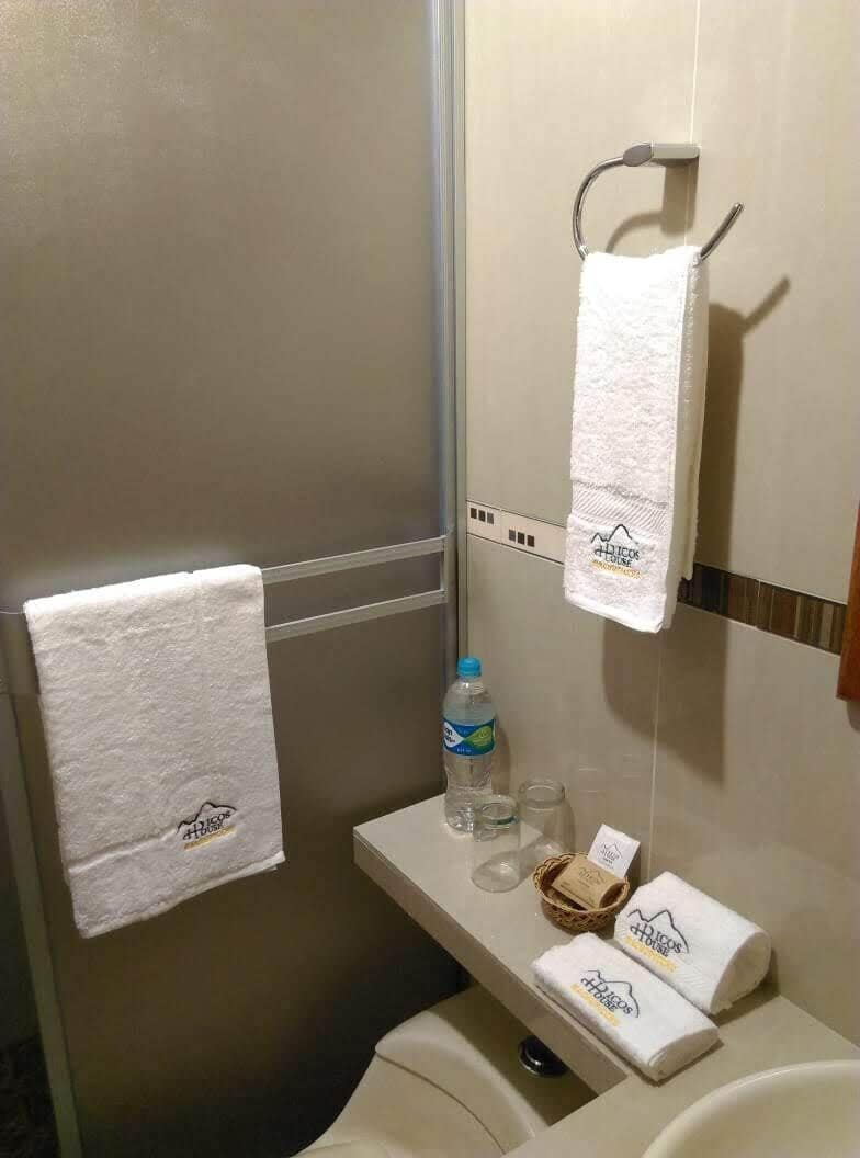 A bathroom with two towels hanging on a rack, a bottle of water, and a small basket on the counter.
