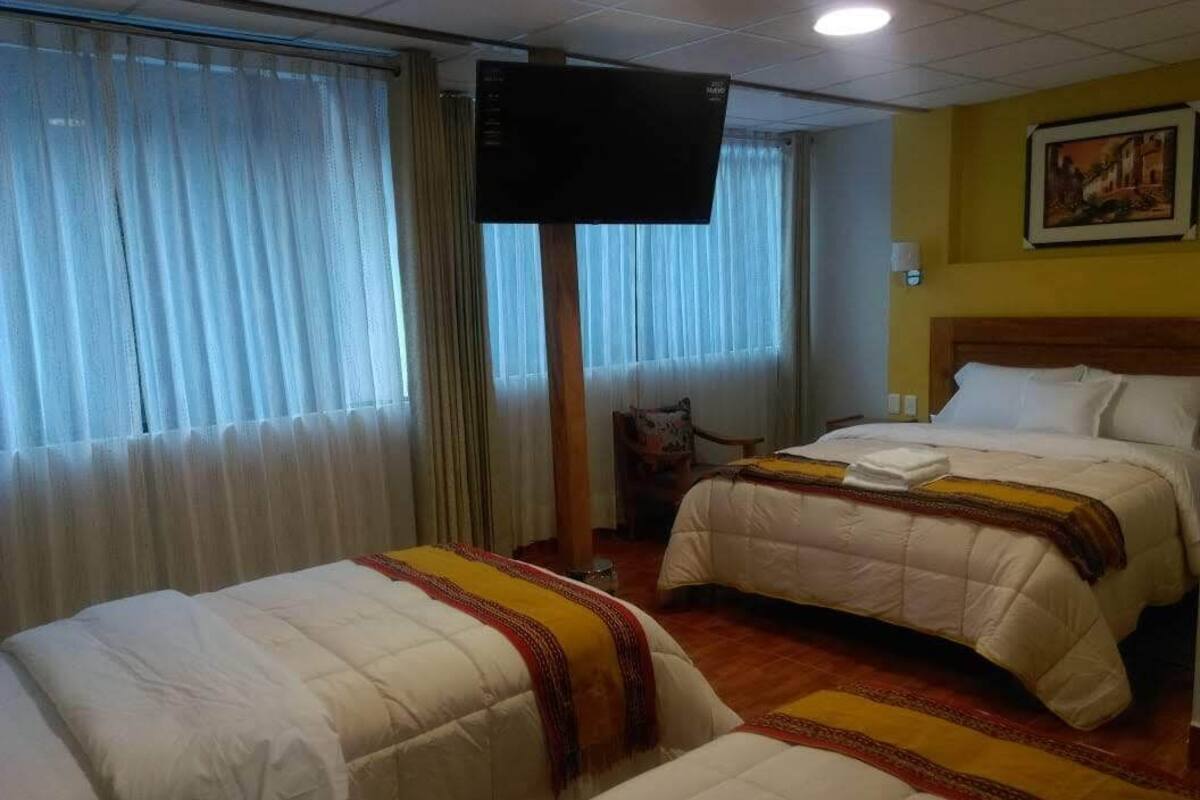 A hotel room with two beds, a television, and a painting on the wall.