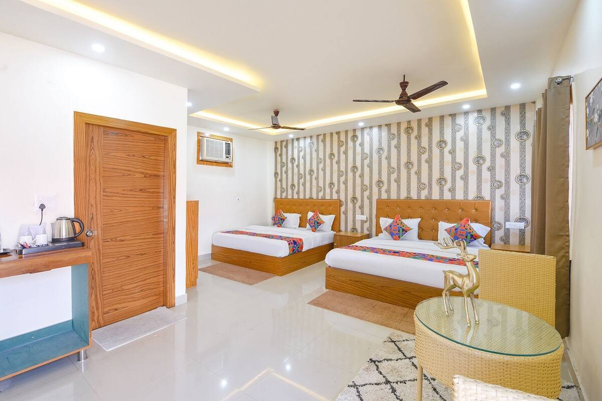 A hotel room with two beds, a ceiling fan, a coffee maker, and a decorative wall.