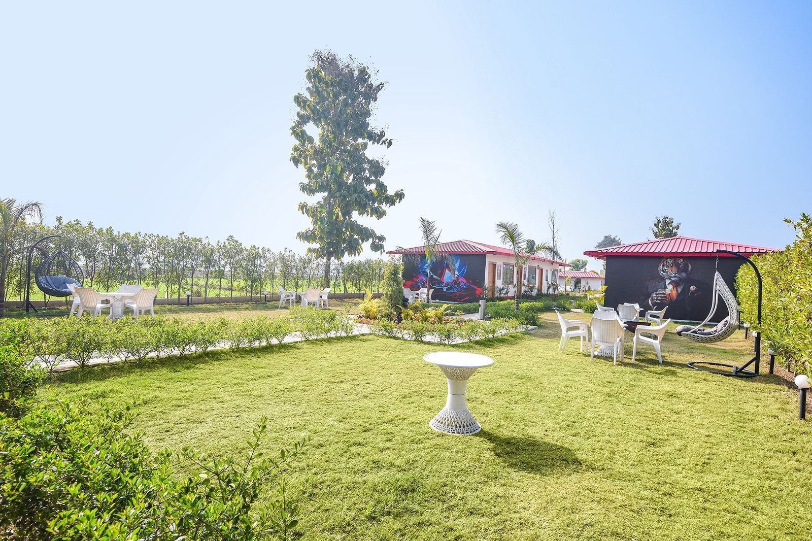A garden with outdoor seating, a hanging chair, and a mural of a tiger.