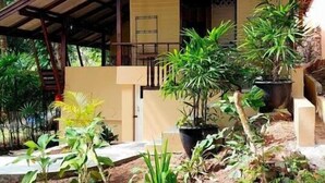A house with a covered porch, potted plants, and a stone pathway.