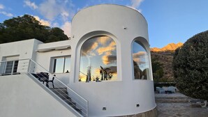 Un edificio moderno con una facciata curva, ampie finestre ad arco e una base in pietra.