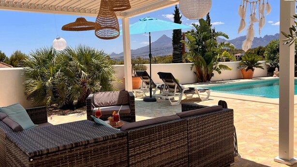 Zona relax all'aperto con mobili in vimini, piscina e vista sulle montagne.