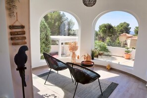 A room with two black chairs, a hanging bird sculpture, and a view through arched windows. - Villa Amira - Altea, Costa Blanca (Altea)