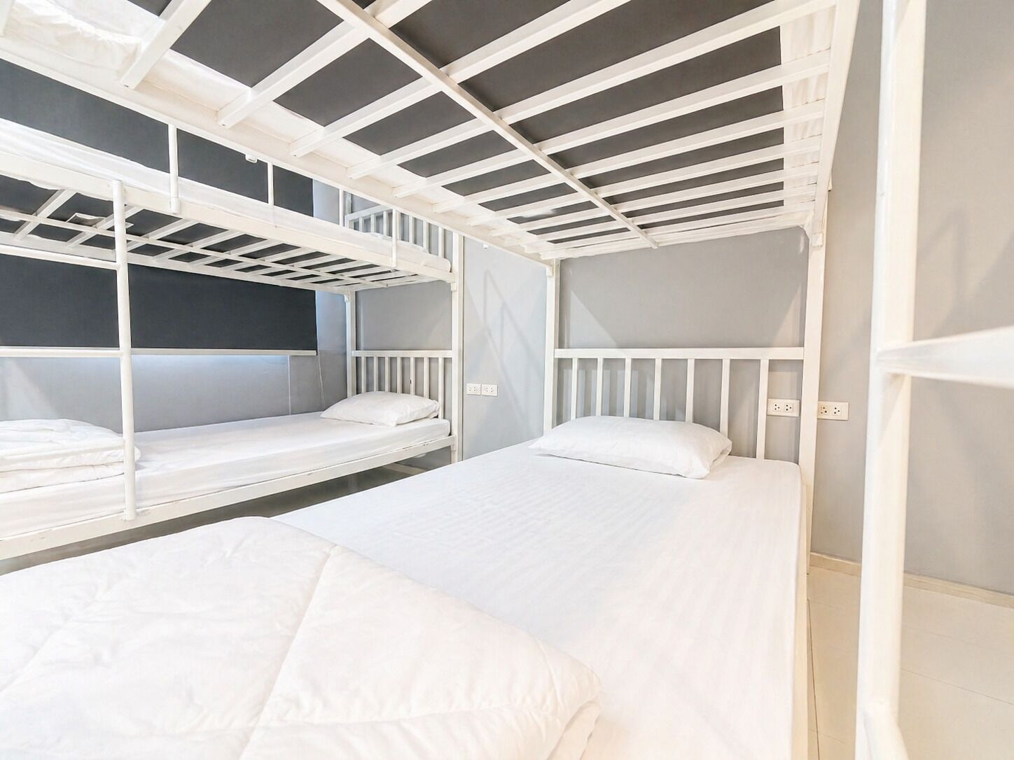 A bunk bed room with white railings and a grey wall.