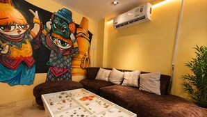 Una sala de estar con un sofá marrón, una mesa de vidrio con caracoles y un mural en la pared.