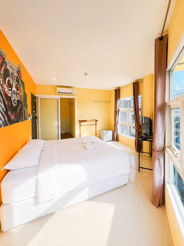 A hotel room with a bed, a bathroom, a window with curtains, and a city view.