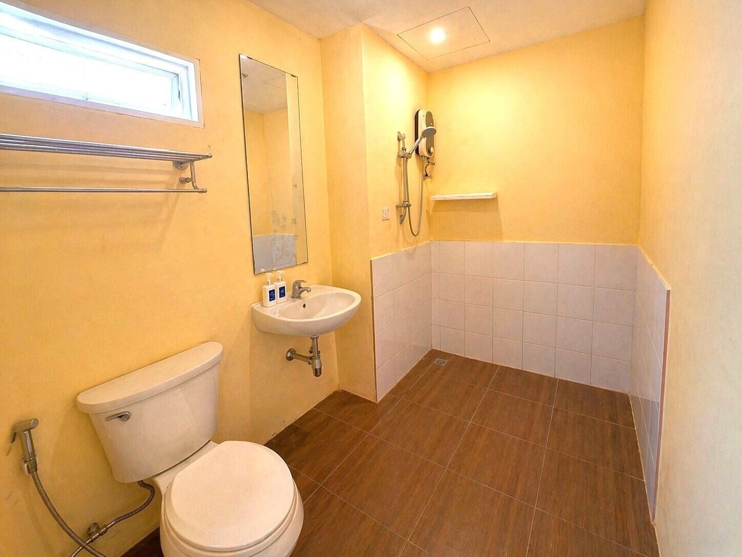 Un baño pequeño con inodoro, lavamanos, espejo, ducha y paredes de azulejos.