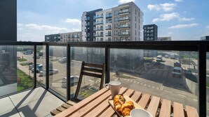 A balcony with a wooden table, a chair, a cup, and a croissant. - Bright Apartment | Parking | Balcony | Remote Work (Poznań)