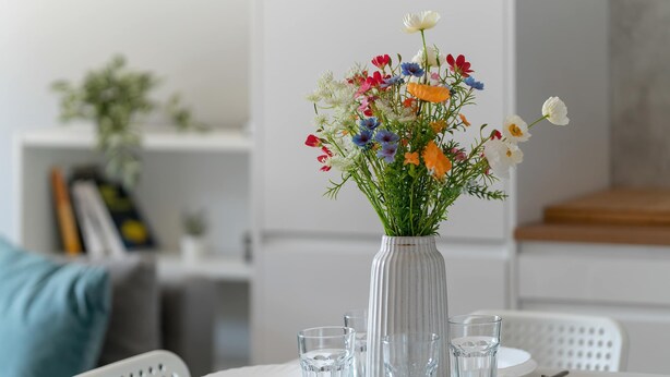 A dining table set with plates, glasses, and cutlery, a vase with flowers, and a white chair. - Bright Apartment | Parking | Balcony | Remote Work (Poznań)
