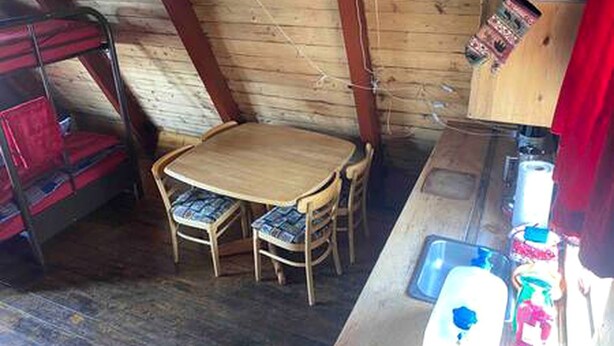 A wooden interior with a bunk bed, a round wooden table with chairs, and a sink with various items. - Rustic Cabin with Spectacular Alpine Views in Walden, Colorado (Walden)
