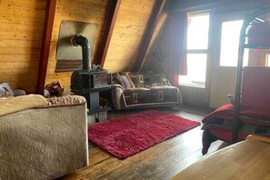 Una habitación acogedora con techo de madera, chimenea, sofá y alfombra roja.
