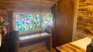 A wooden cabin interior with a stained glass window, wooden walls, and a bench. - Rustic Cabin with Spectacular Alpine Views in Walden, Colorado (Walden)