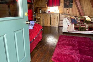 A cozy room with a bed, a red rug, and a wooden staircase. - Rustic Cabin with Spectacular Alpine Views in Walden, Colorado (Walden)