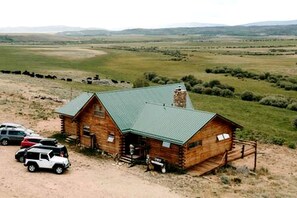 A log cabin with a green roof, a porch, and a dirt driveway. - Cabin Rental for Large Groups Ideal for Colorado Glamping (Walden)