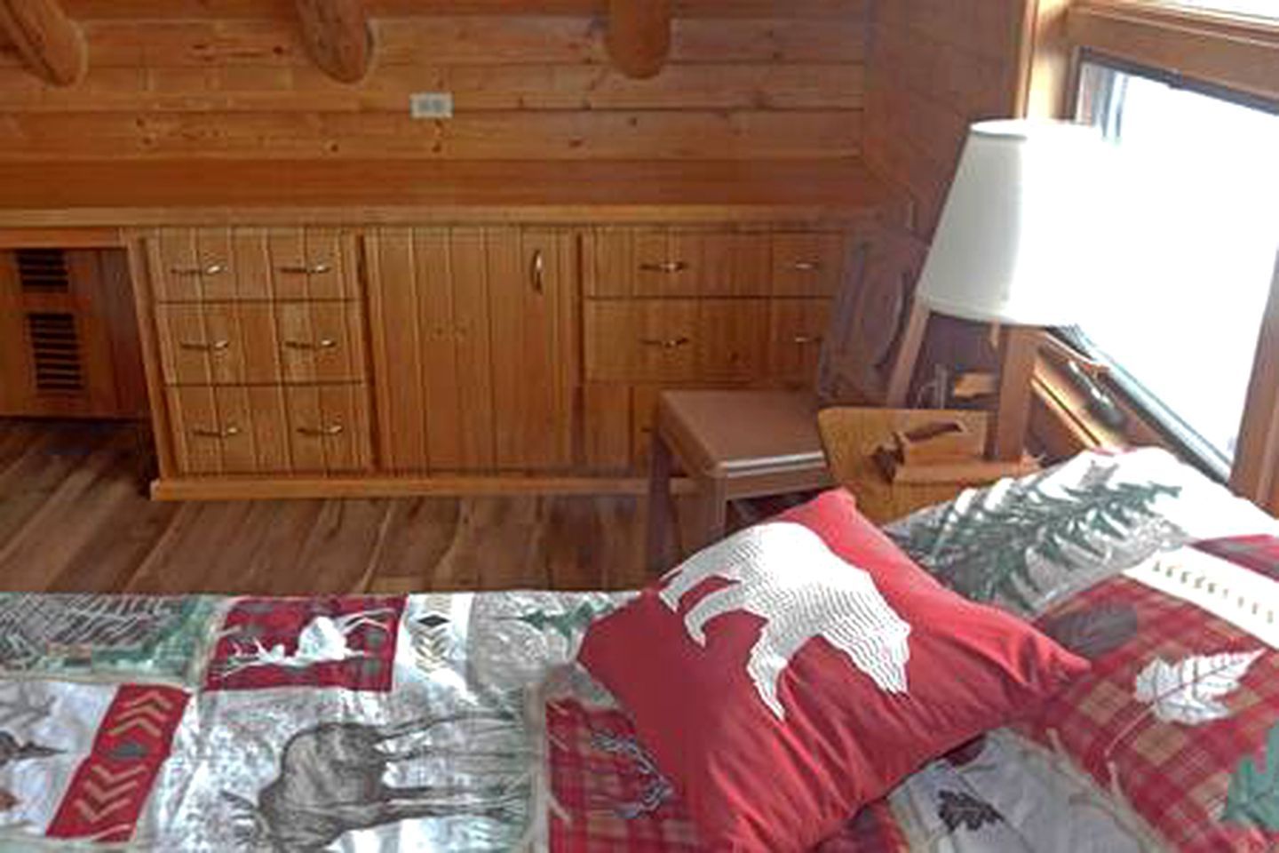 Ein Holzblock-Innenraum mit einem Bett, einem Schreibtisch und einem Fenster.