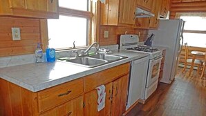 A kitchen with wooden cabinets, a sink, a stove, and a refrigerator. - Cabin Rental for Large Groups Ideal for Colorado Glamping (Walden)