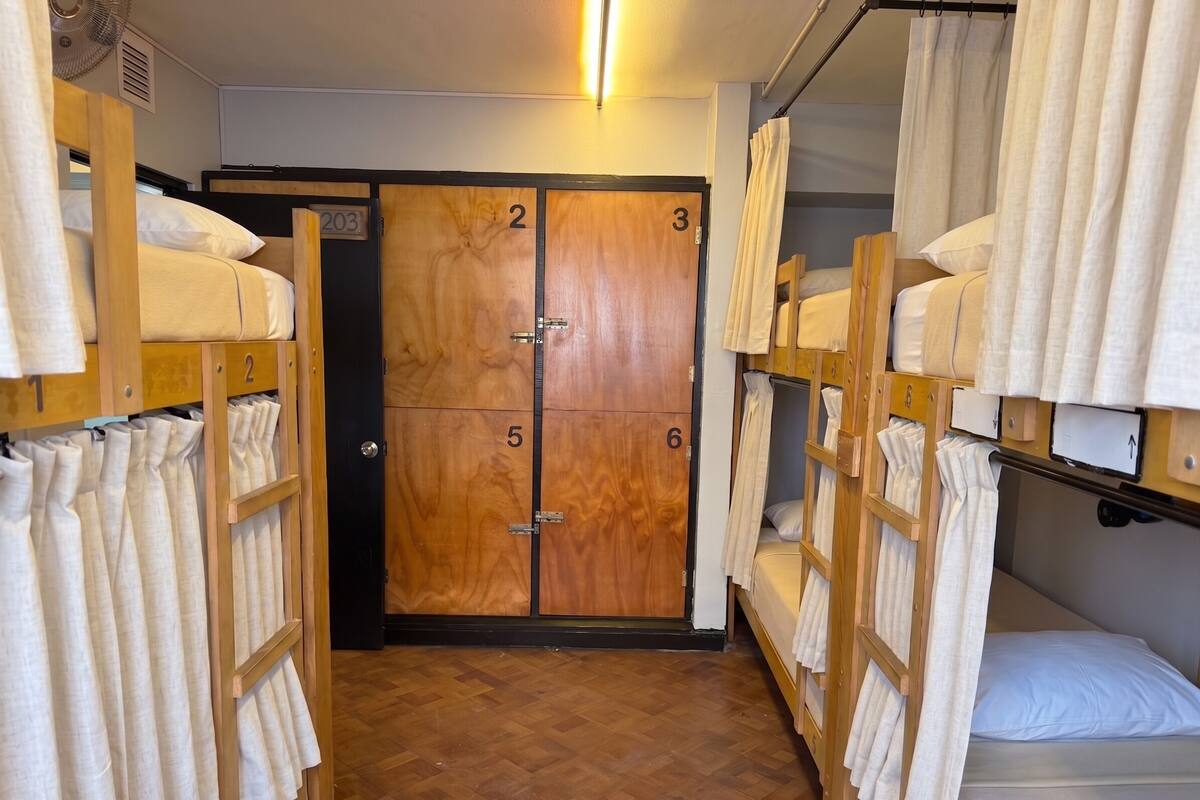 A hotel room with bunk beds, wooden doors numbered 2, 3, 5, and 6, and a hallway with towels on racks.