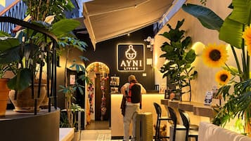 A hotel lobby with a reception desk, seating area, and potted plants.