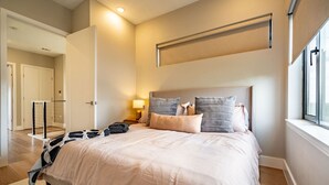 A modern bedroom with a large bed, bedside tables, a lamp, and a view of the hallway. - Modern Townhome | Fire Pit, Telescope, By Magnolia (Fort Worth)