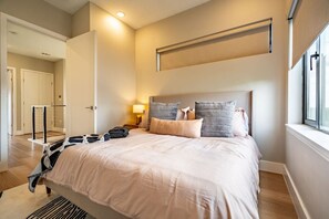 Une chambre moderne avec un grand lit, des tables de chevet, une lampe et une vue sur le couloir.