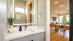 A modern bathroom with a large mirror, a sink, and a potted plant. - Modern Townhome | Fire Pit, Telescope, By Magnolia (Fort Worth)