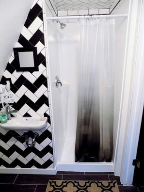 Un baño con ducha, lavamanos y espejo.