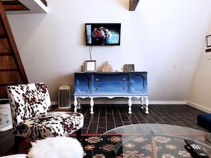 A living room with a blue cabinet, a television mounted on the wall, and a patterned rug.