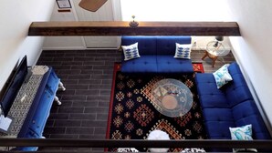 A room with a ceiling fan, a blue sofa set, a patterned rug, and a small round table.