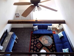 A room with a ceiling fan, a blue sofa set, a patterned rug, and a small round table.