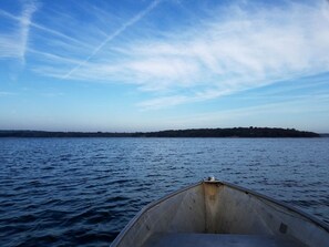 Un bote sobre aguas tranquilas, cielo despejado y una costa lejana.