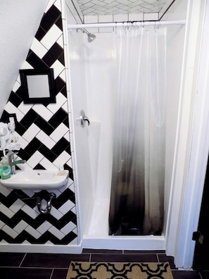 A bathroom with a shower, a sink, and a mirror.