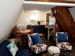 Un acogedor espacio tipo loft con comedor, cocina y una escalera.