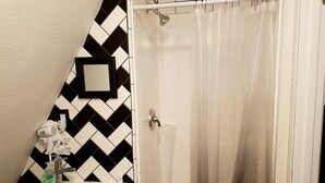 A bathroom with a black and white chevron-patterned wall, a white sink, a shower curtain, and a hairdryer plugged in.