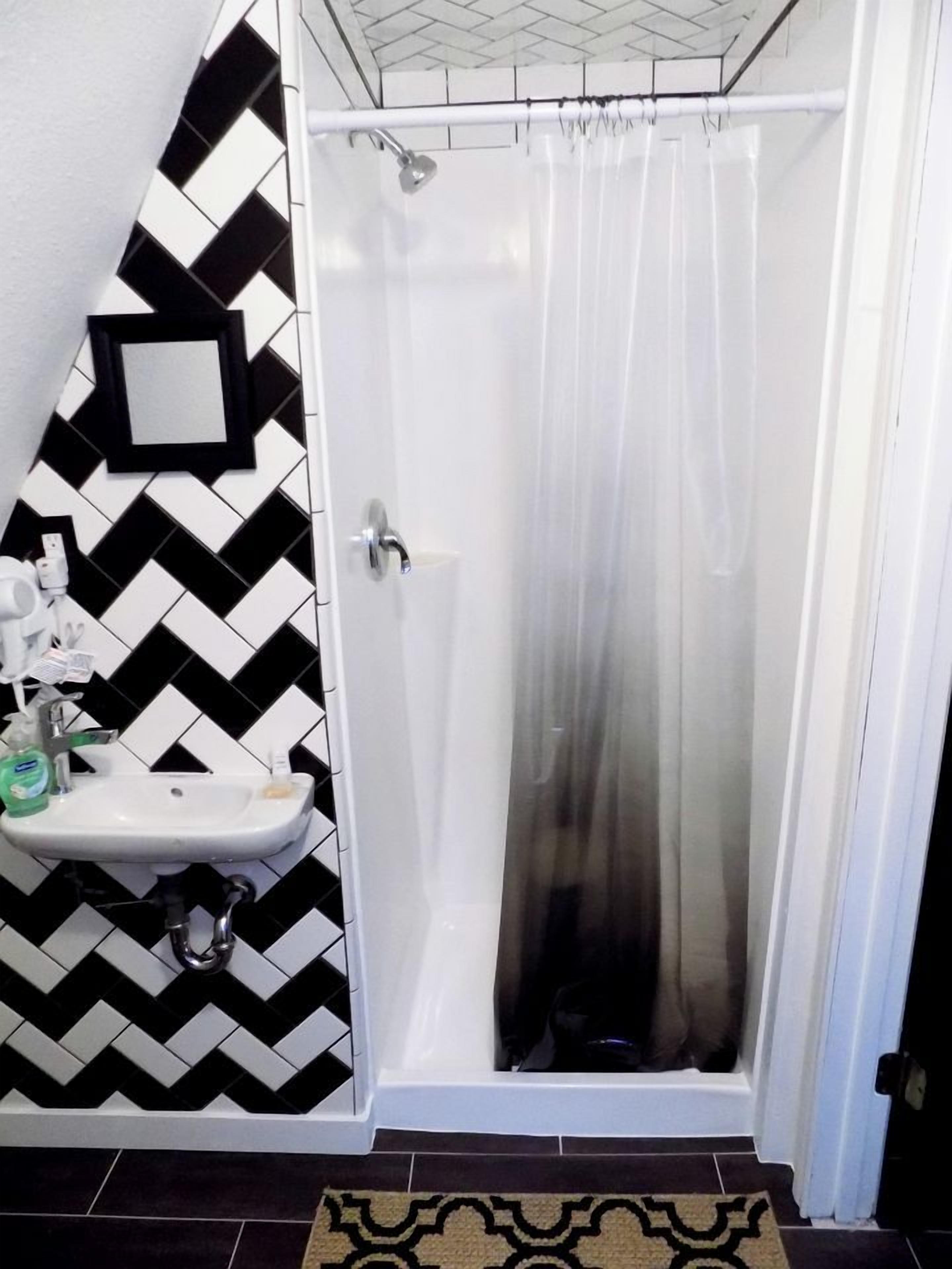 A bathroom with a shower, a sink, and a mirror.