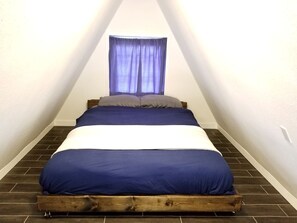 Un dormitorio con cama, ventana con cortinas y suelo de madera.