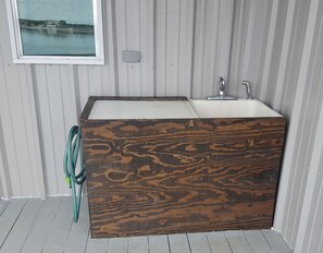 Une salle de bain avec un meuble-lavabo en bois, une fenêtre et une vue sur un plan d’eau.