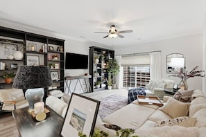 A modern living room with a sofa, a coffee table, a TV, and a bookshelf.
